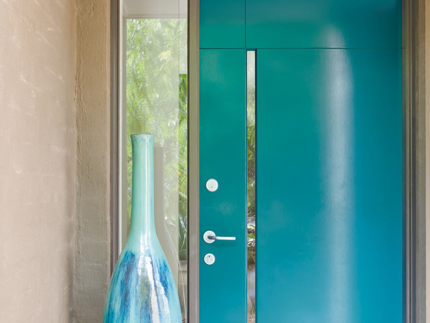 Exterior blue doorway with neutral painted brick and silver furnishings and vase